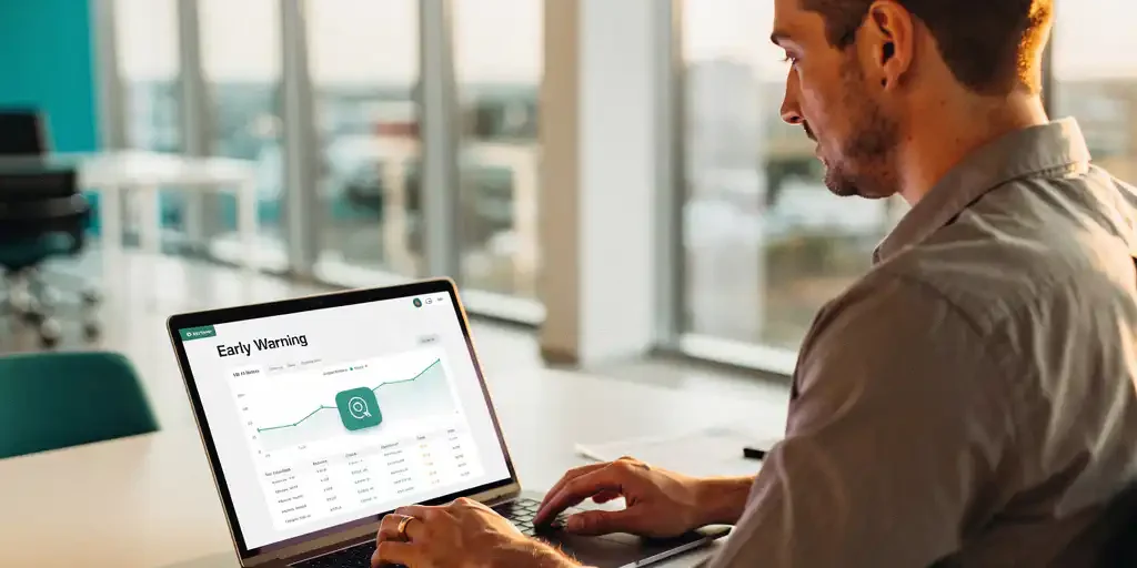 HR-manager bekijkt vroegwaarschuwingsdashboard op laptop in licht modern kantoor met warm natuurlijk licht.