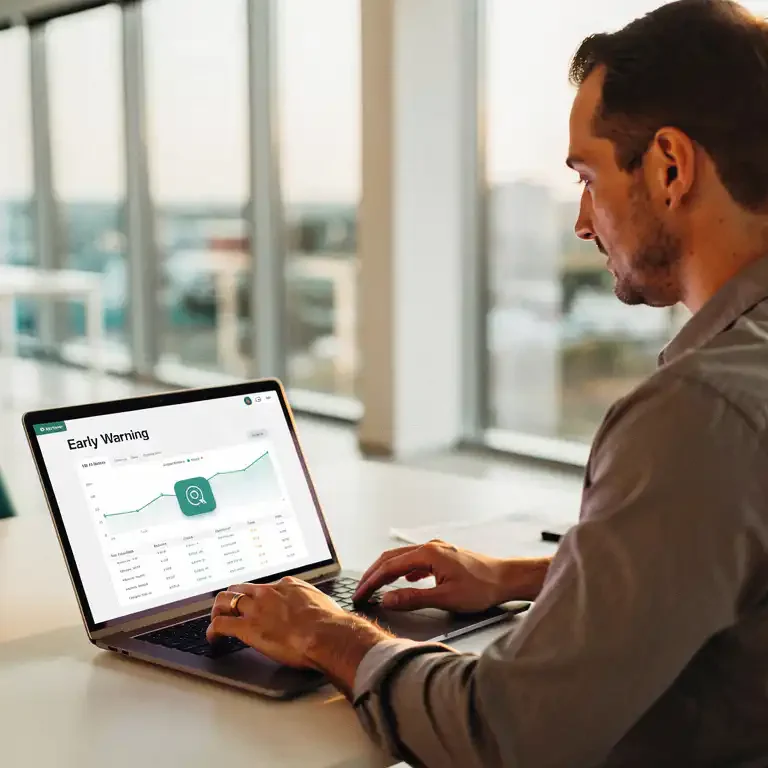 HR-manager bekijkt vroegwaarschuwingsdashboard op laptop in licht modern kantoor met warm natuurlijk licht.